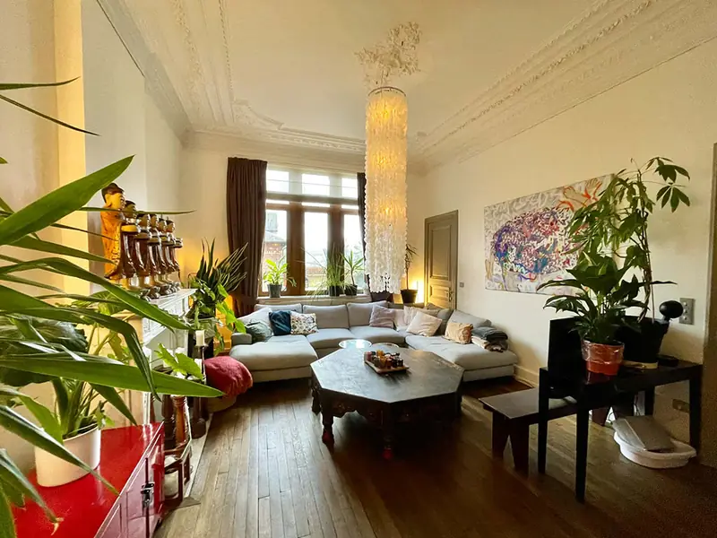 The salon at Villa O with art, plants and Art Nouveau ceilings